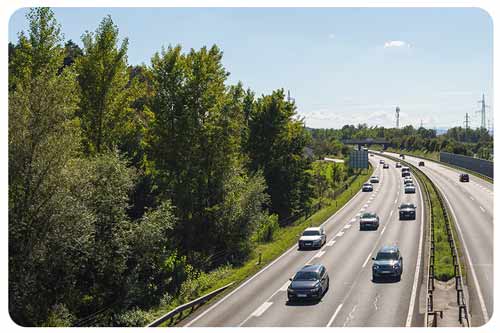 Cars drving along an Ontario highway surrounded by green trees.