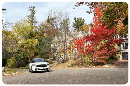 A white compact car drives along a colorful street