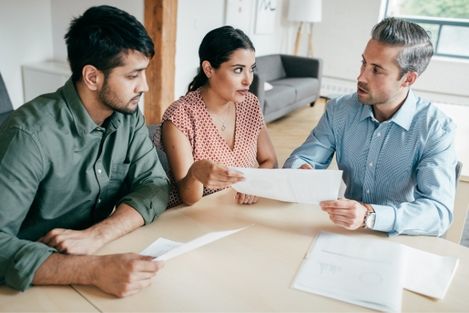 couple talking to insurance broker over a pile of documents