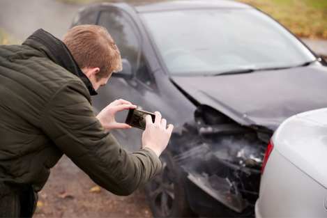 man taking photos on his phone of a car accident