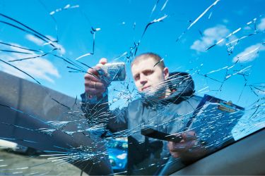 man taking a photo of broken windshield on car