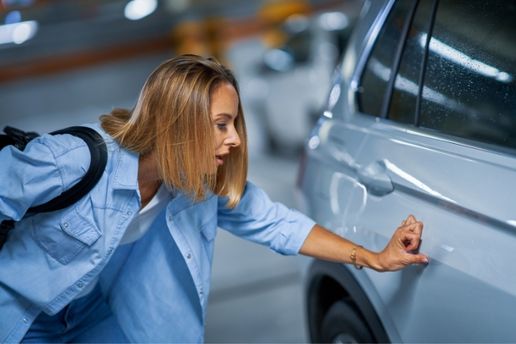 Frustrated woman looking at damage on her car from a hit and run