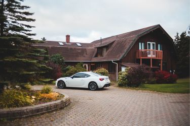 white sports car parked outside rustic brown house